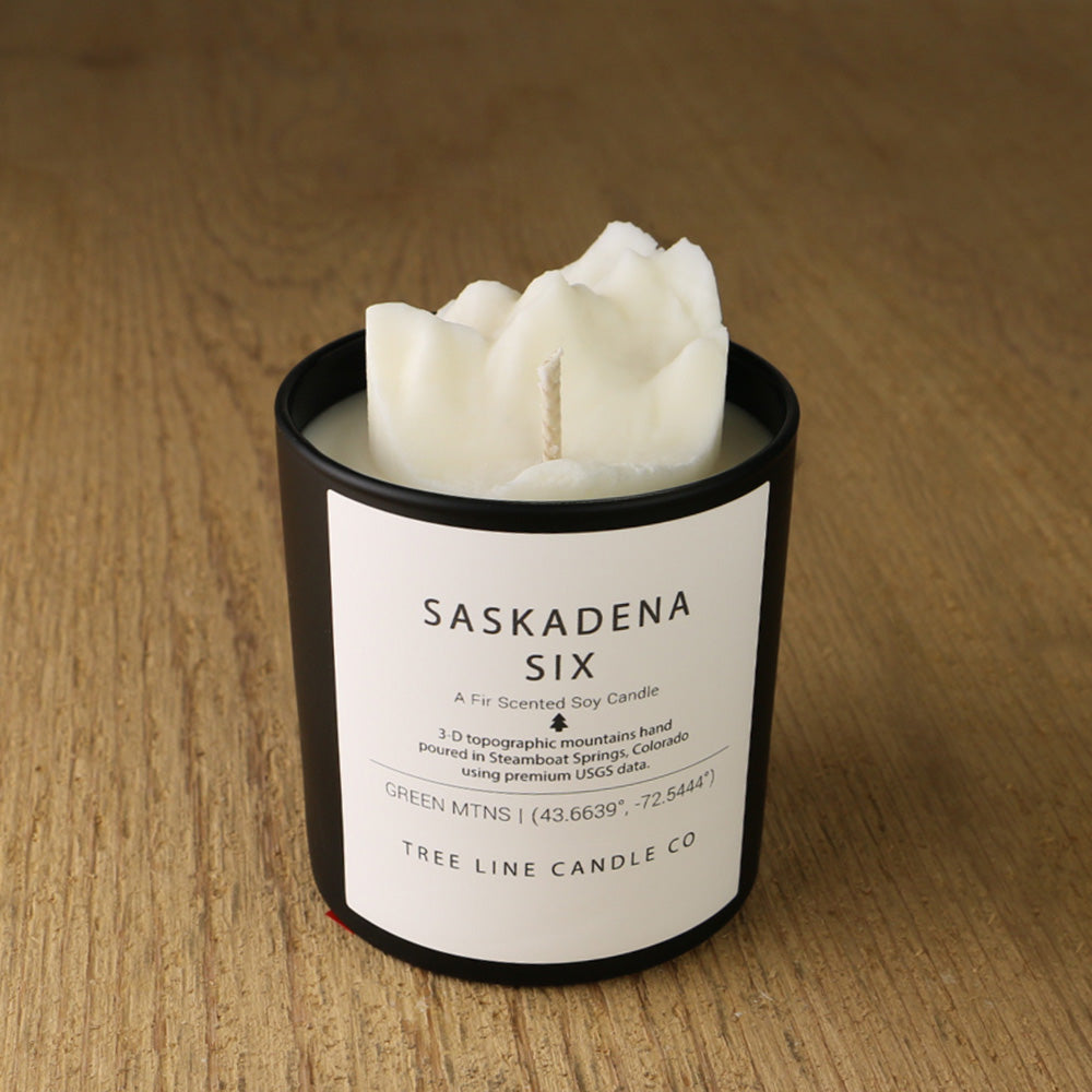  A white soy wax replica candle of Saskadena Six in a round, black glass.