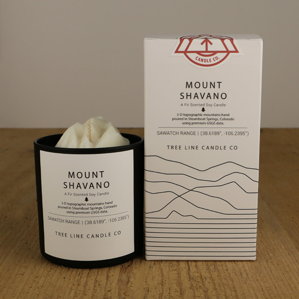 A white wax candle replica of Mount Shavano is next to a white box with red and black lettering.