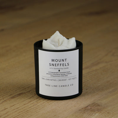 A white soy wax replica candle of Mount Sneffels in a round, black glass.
