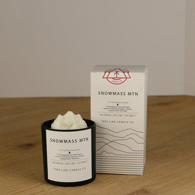 A white wax replica candle of Snowmass Mountain  next to a white box with red and black lettering.