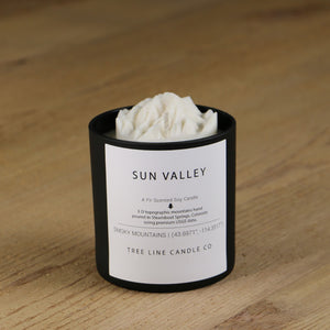  A white soy wax replica candle of Sun Valley in a round, black glass