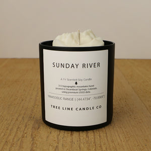  A white soy wax replica candle of Sunday River in a round, black glass.