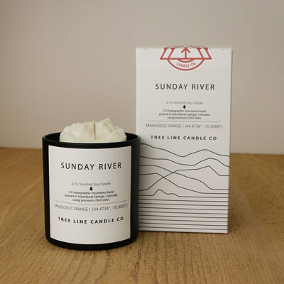 A white wax candle named Sunday River is next to a white box with red and black lettering.
