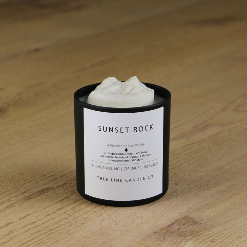  A white soy wax replica candle of Sunset Rock in a round, black glass