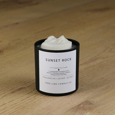  A white soy wax replica candle of Sunset Rock in a round, black glass