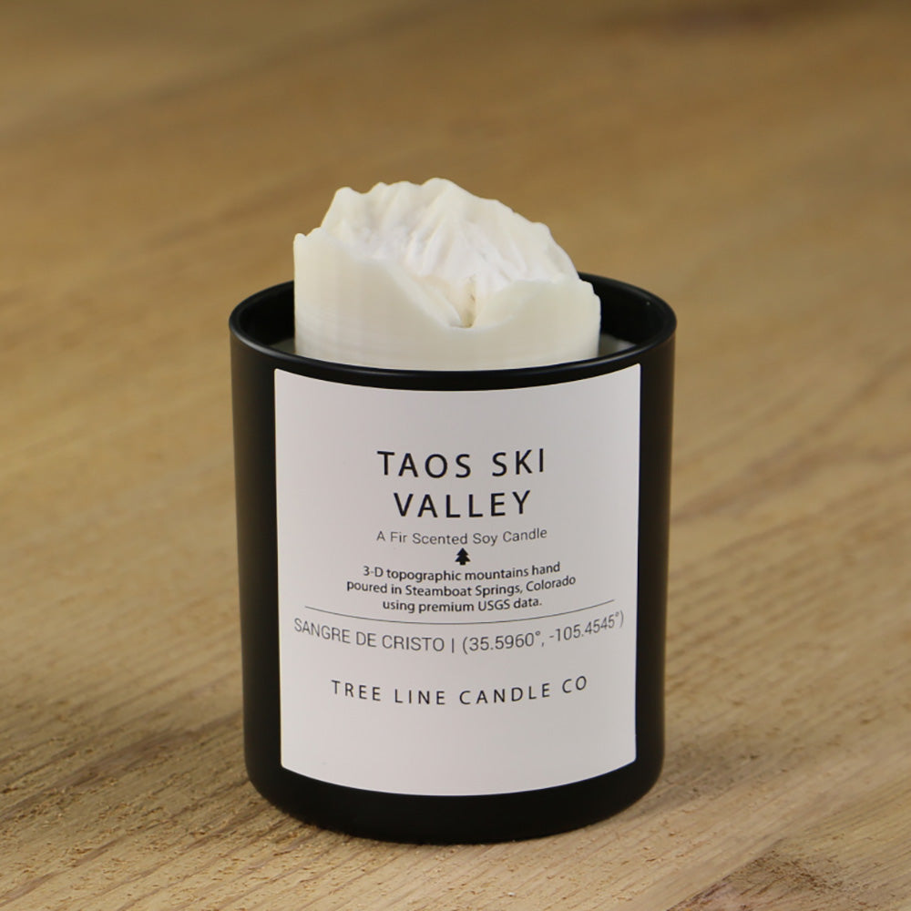  A white soy wax replica candle of Taos Ski Valley in a round, black glass