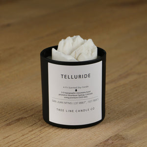  A white soy wax replica candle of  Telluride in a round, black glass.