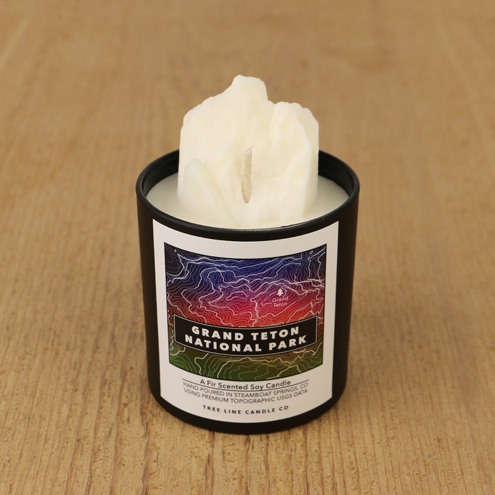  A white soy wax replica candle of Grand Teton in a round, black glass.