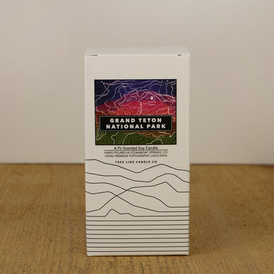 A white box with a blue, red and green label with topography lines by Tree Line Candle Co.