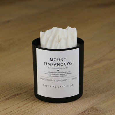 A white soy wax replica candle of Mount Timpanogos in a round, black glass.