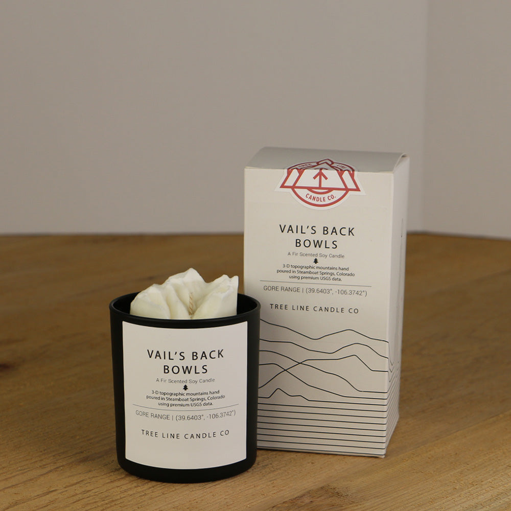 A white wax replica candle of Vail’s Back Bowls next to a white box with red and black lettering.