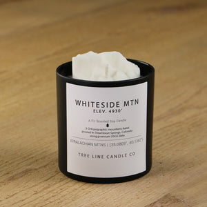  A white soy wax replica candle of Whiteside Mtn. in a round, black glass.