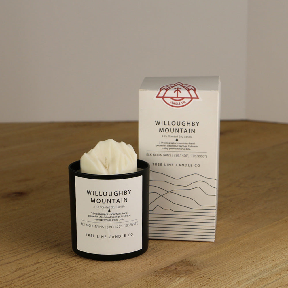 A white wax replica candle of Willoughby Mountain next to a white box with red and black lettering.