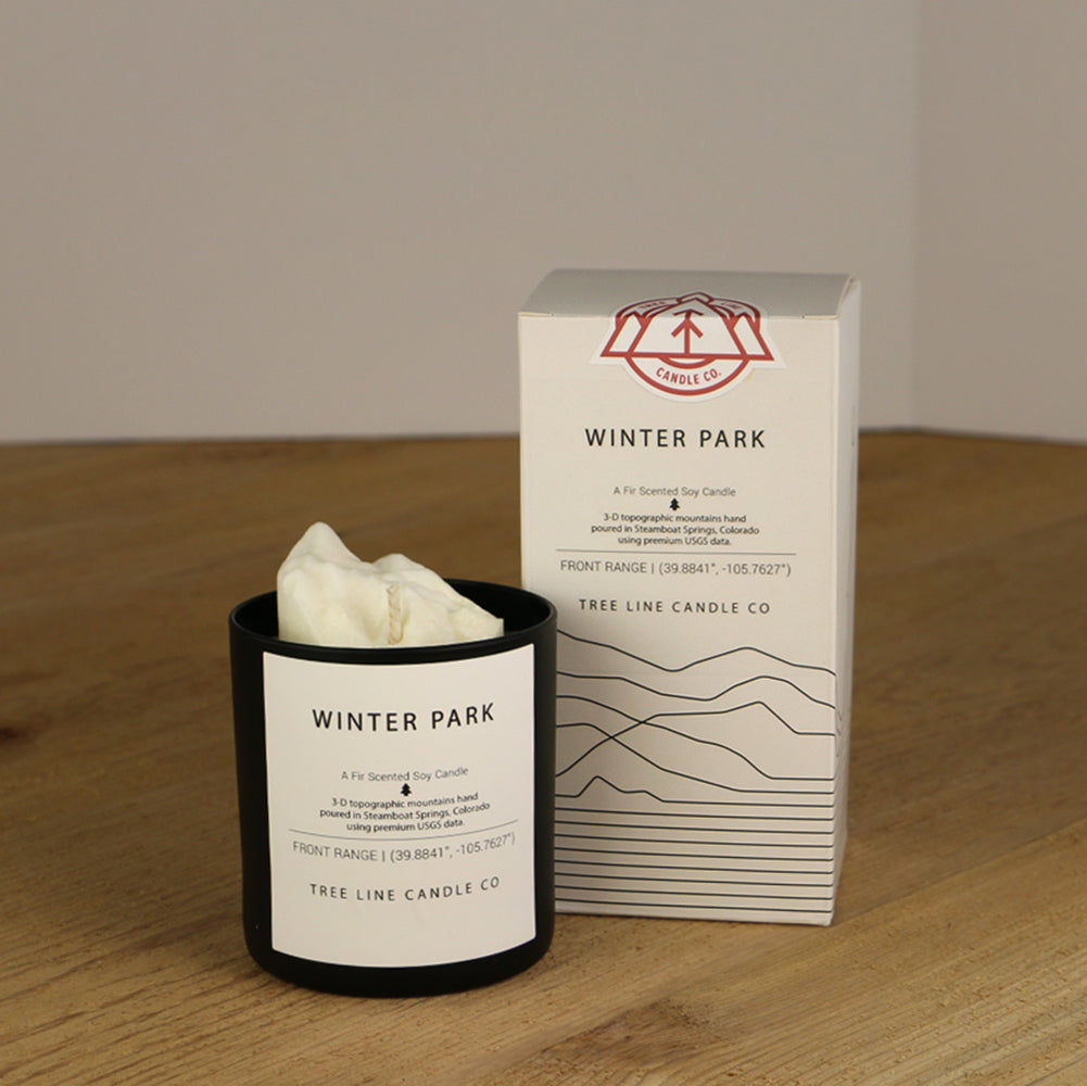 A white wax replica candle of Winter Park next to a white box with red and black lettering.